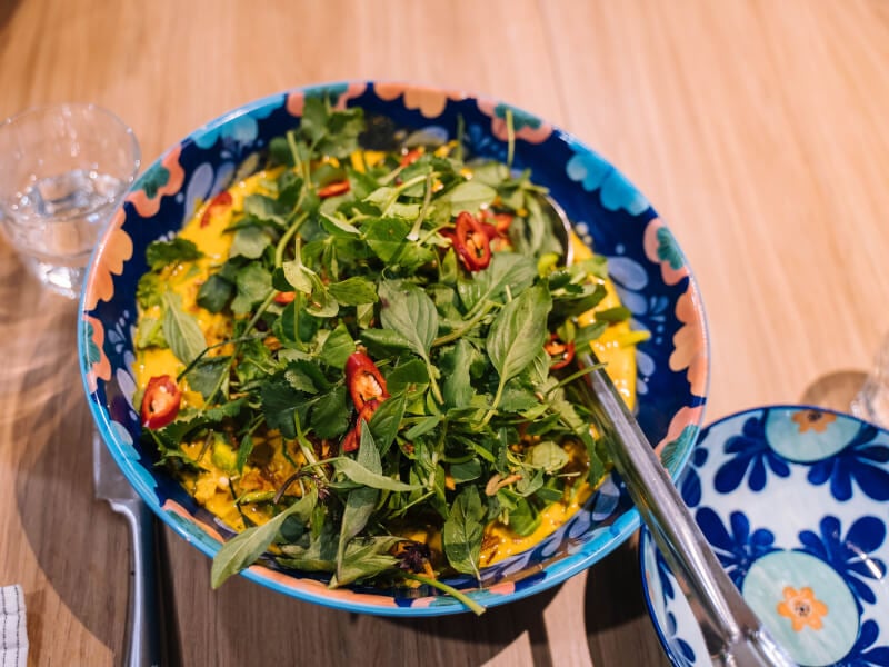 A bowl of yellow curry topped with lots of green leaves from a cooking course.